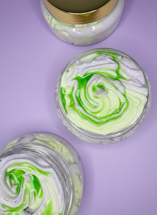 Green and white swirled dessert in a clear container on a textured green and purple surface.